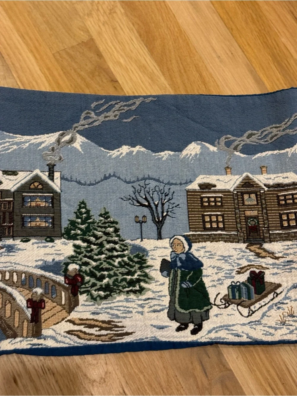 holiday-themed tapestry table runner featuring a snowy village 64”